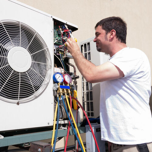 An HVAC Technician Adjusts Wires on an Air Conditioner.